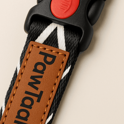 Close-up of PawTaaka black dog collar showing reinforced nylon material, red safety buckle, and stitched logo tag for premium quality.