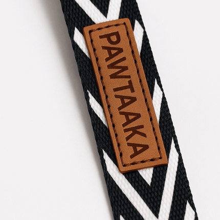 Close-up of PawTaaka logo on black-and-white zigzag dog leash, highlighting premium stitching and modern monochrome design.